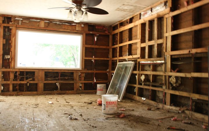 Room stripped to the studs after flood damage, with the ceiling fan still in place
