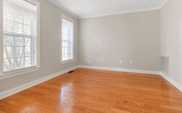Empty room with gray walls, a wood floor and daylight from two windows