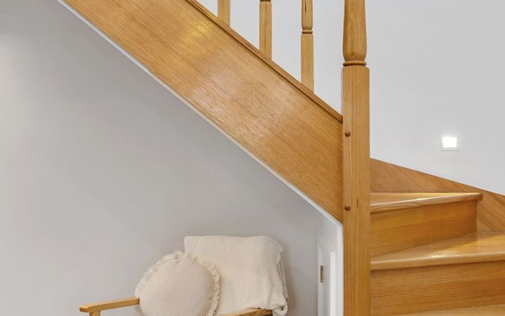 Wooden staircase along a white wall, with a chair tucked beneath the stairs