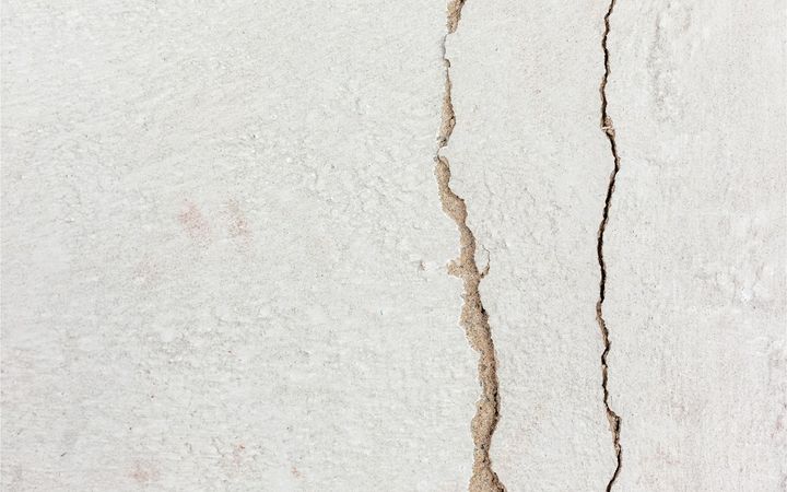 Two long cracks running across a white painted surface
